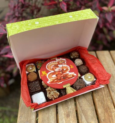 Mix Box con 20 postres surtidos, incluyendo brownies, alfajores y trufas, decorados con fondant del Año Nuevo Chino 2026 del Caballo y monedas chinas.