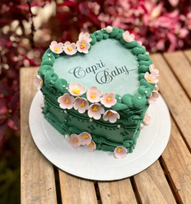 Burncake en forma de corazón decorado con flores en 3D alrededor de la tortita, con un diseño delicado y romántico.