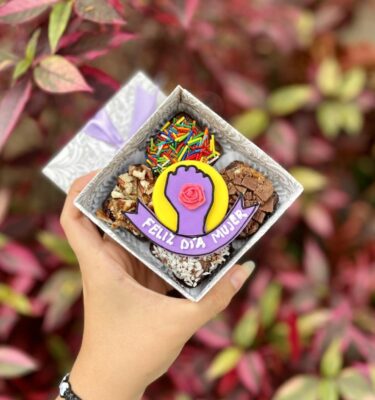 Mini four con 4 brownies y una decoración central de puño levantado con un pequeño banner que dice “Feliz Día Mujer”.
