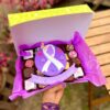 Mix box con 20 postres variados (brownies, alfajores y trufas) con decoración central en fondant del Día de la Mujer con lazo morado y silueta de rostro femenino, acompañado de un banner que dice “Juntas, libres y sin miedo”.